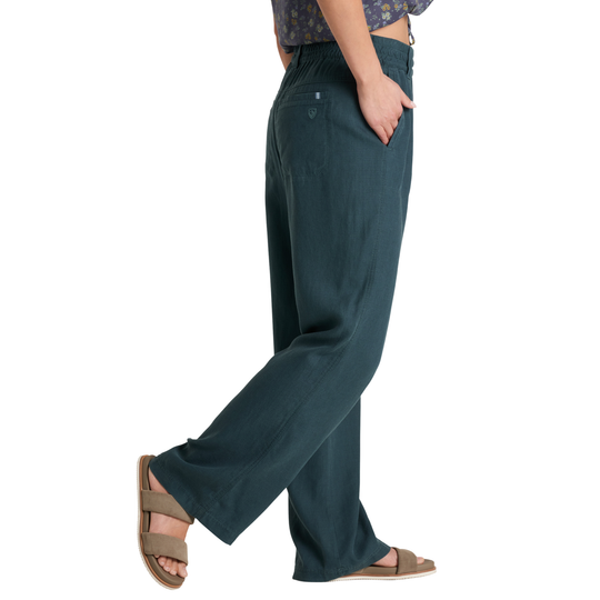 A side view of a person wearing dark teal wide-leg pants with a matching patterned top and brown slide sandals, shown against a plain white background.