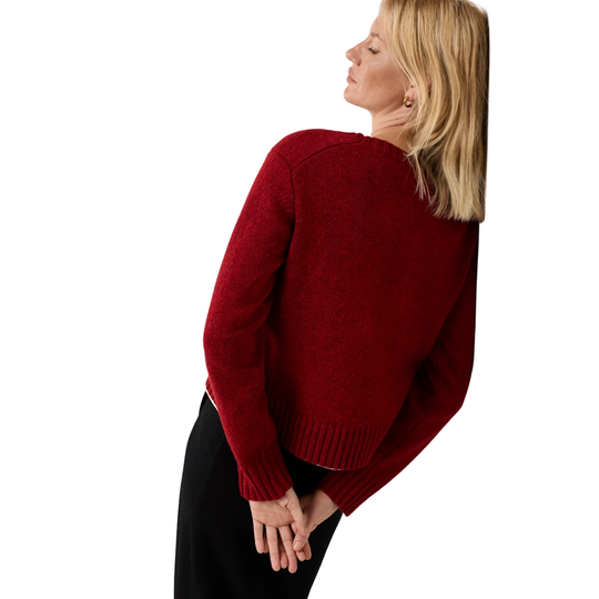 A woman shown from the back wearing a deep red knit sweater and black pants, photographed against a plain white background.