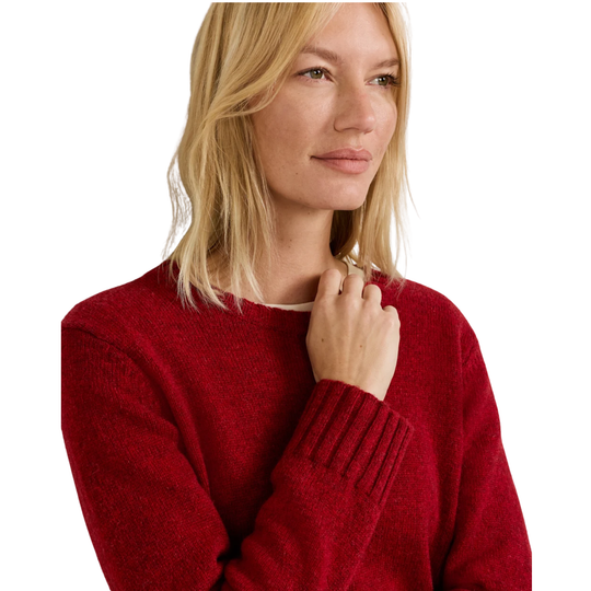 A blonde woman wearing a textured red knit crewneck sweater, shown from the chest up against a plain white background.