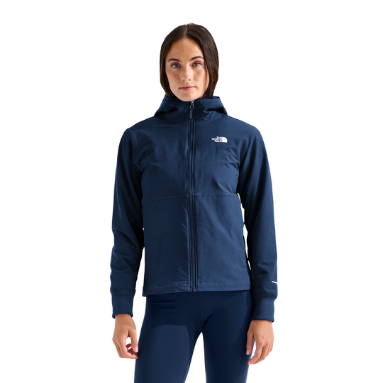 A woman modeling a navy blue hooded zip-up jacket with a white embroidered The North Face logo on the left chest, paired with matching navy leggings, against a solid white background.