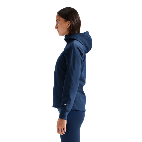 A woman modeling a navy blue hooded zip-up jacket with a white embroidered The North Face logo on the left chest, paired with matching navy leggings, against a solid white background.