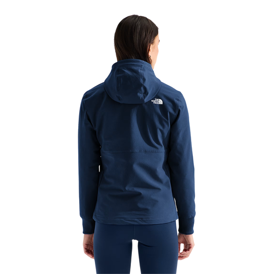 A woman modeling a navy blue hooded zip-up jacket with a white embroidered The North Face logo on the left chest, paired with matching navy leggings, against a solid white background.