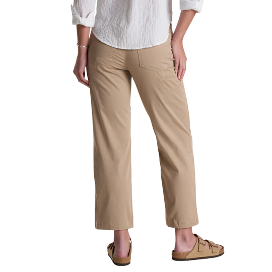 A person shown from the waist down wearing tan cropped pants, a white blouse, and tan slide sandals against a plain white studio background.