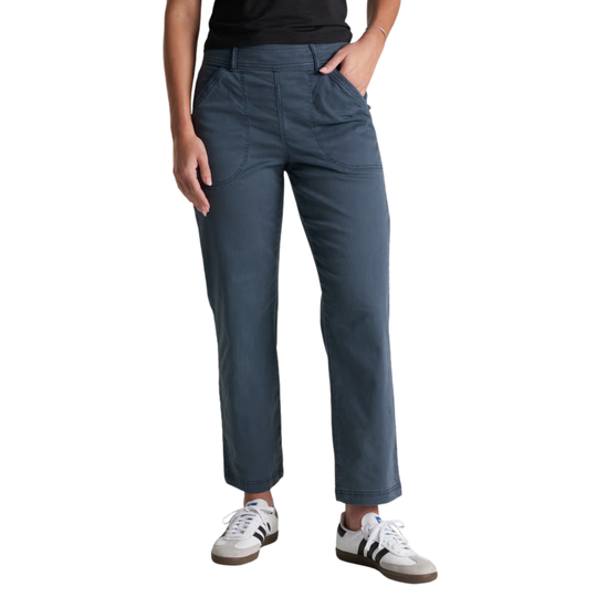 A person wearing a pair of dark blue straight-leg pants with a black top and white sneakers, shown from the waist down on a plain white background.