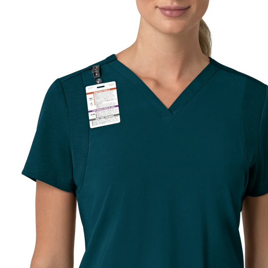 Teal V-neck scrub top with short sleeves and a clipped product tag on the left shoulder.