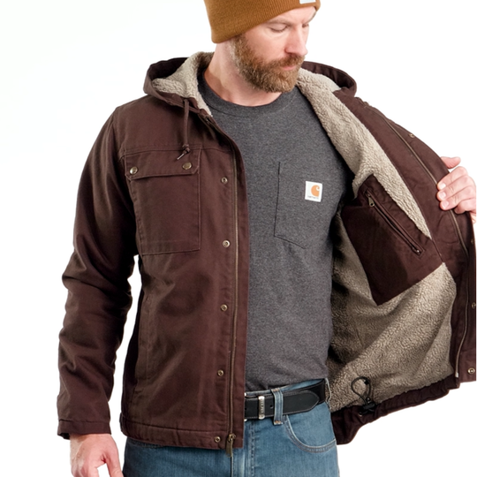 Man wearing a brown jacket with a hood, gray shirt, and blue jeans on a white background