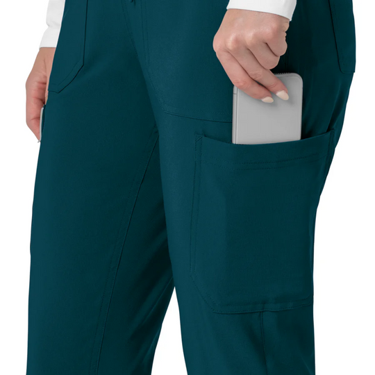 Teal cargo scrub pants with large side pocket, shown on model holding a phone