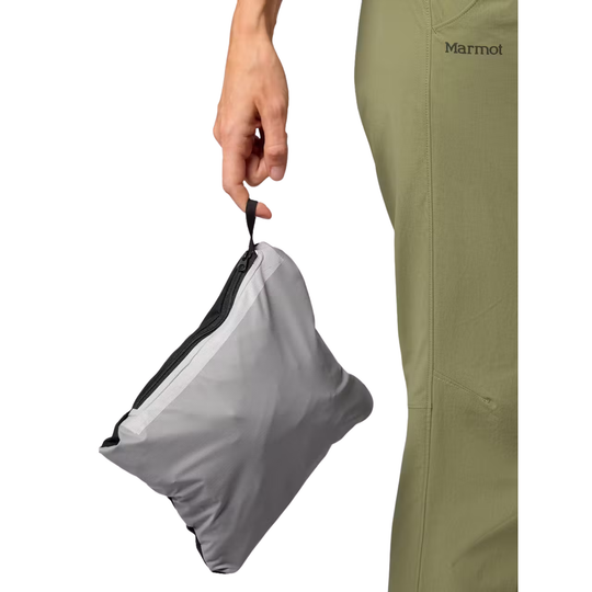 A person holds a small gray Marmot bag by its zipper handle, with the person's hand and olive green pants visible against a plain white background.