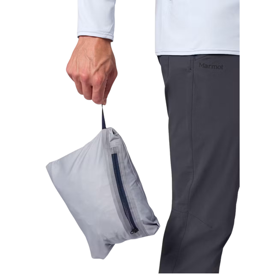 A person wearing dark gray Marmot pants holds a light gray zippered pouch against a white background.