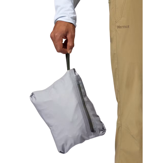 A person holds a small light gray zippered pouch by a black handle, shown next to tan Marmot pants on a white background.