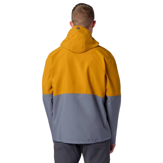 A man viewed from behind wearing a colorblock hooded jacket with a mustard yellow upper section and a slate gray lower section, paired with dark gray pants, against a plain white background.