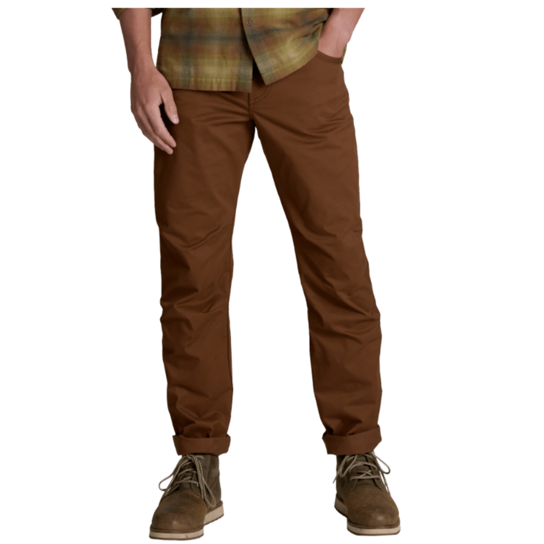 A person wearing brown straight-leg pants with a plaid shirt and brown lace-up boots, shown from the waist down on a plain white background.