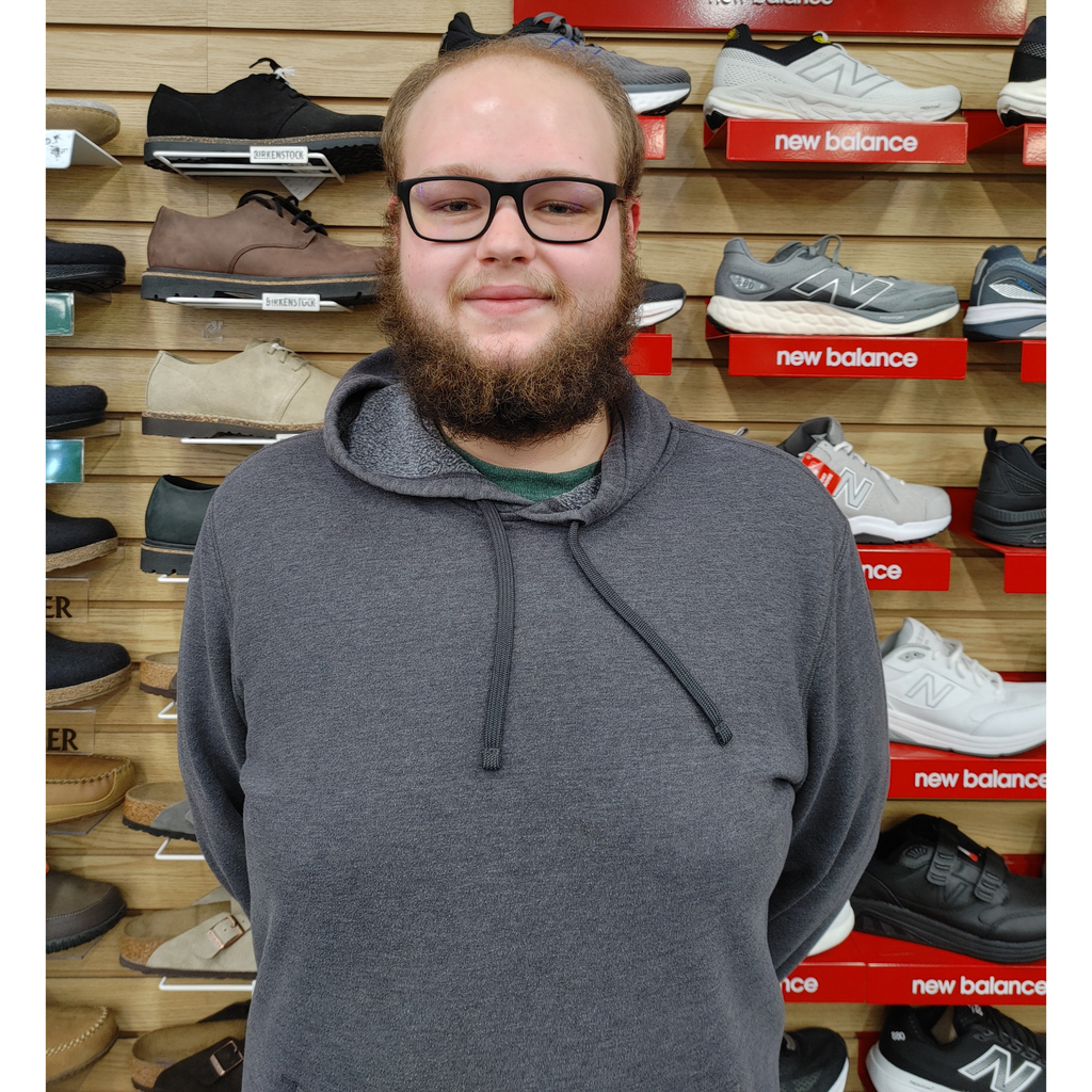 Xander profile picture standing in front of New Balance display 