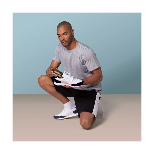 White and navy athletic shoe with gum sole and breathable mesh upper