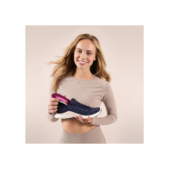 Dark navy running shoe with a pink orthotic insole, shown held by a woman against a light background.