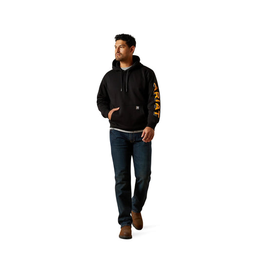 Black pullover hoodie with orange sleeve lettering, front kangaroo pocket, and drawstring hood, worn with jeans and boots