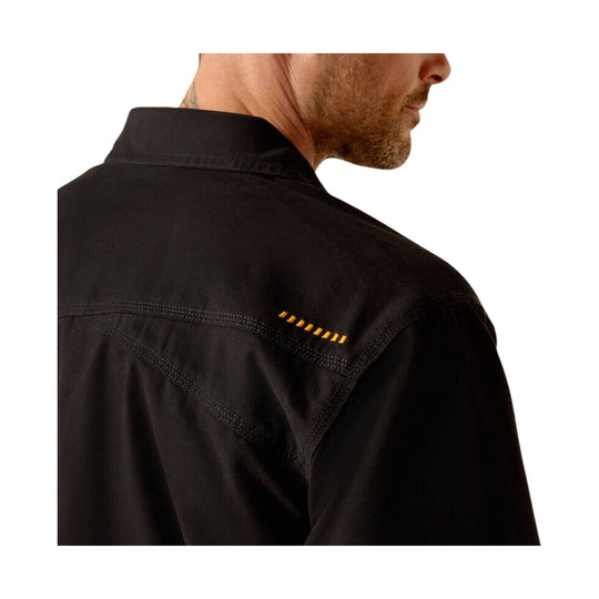 Black long-sleeve work shirt seen from the back, with contrast shoulder stitching and small yellow detail on the upper back.