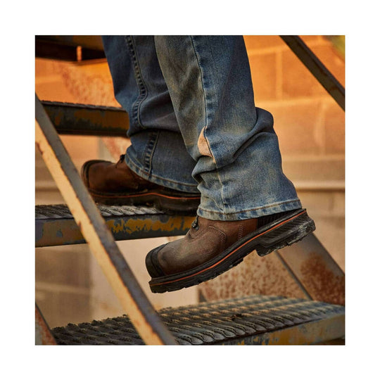 Brown leather work boots with black lug soles on a metal stairway