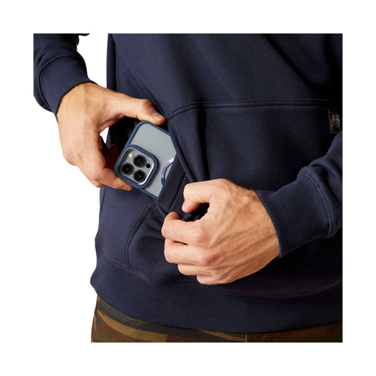 Navy hoodie with a front kangaroo pocket and sleeve cuffs, shown with hands holding a phone at the pocket opening