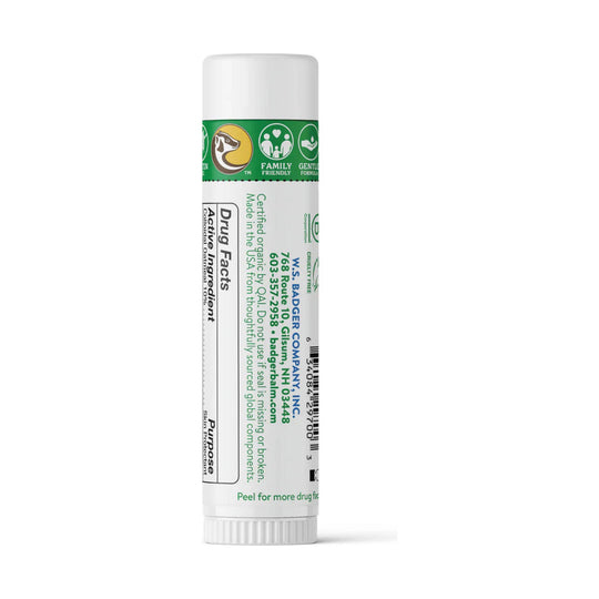 White lip balm tube with green label and capped top, showing Drug Facts and active ingredient text