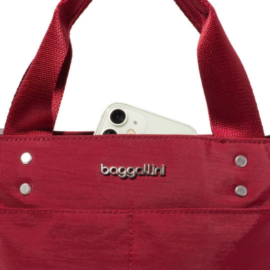 Red canvas tote bag with metal rivets and a small raised logo on the front