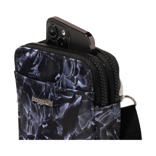 Compact black patterned crossbody bag with front pocket and a phone partially tucked inside