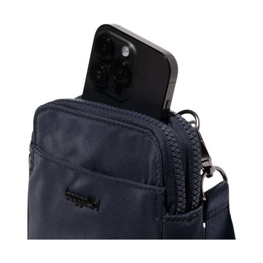 Navy crossbody bag with front zip pocket and smartphone peeking out
