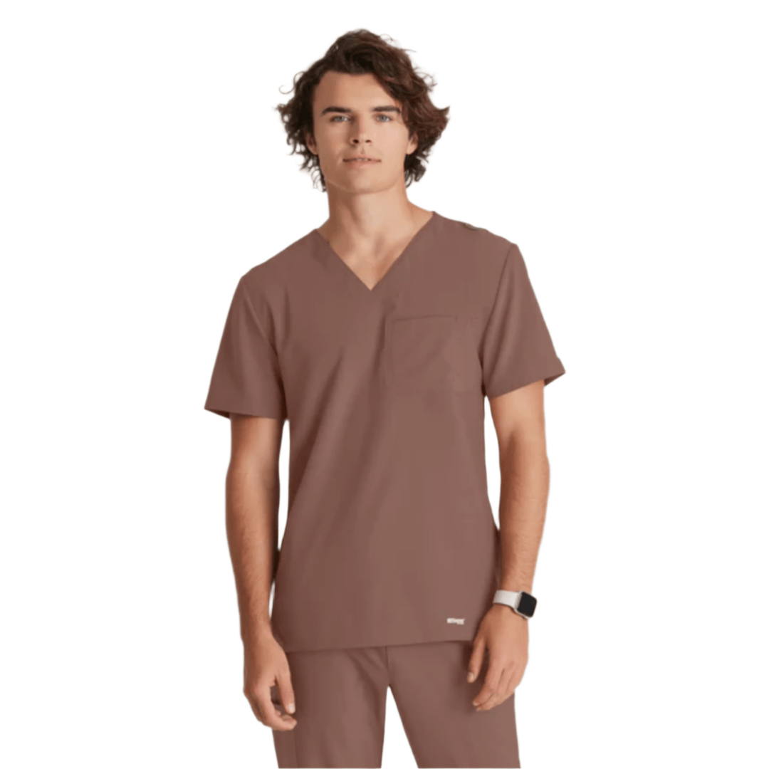 Brown V-neck short-sleeve scrub top with chest pocket, shown on a model against a white background.