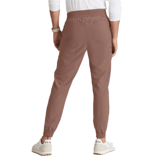 Brown jogger scrub pants shown from the back with elastic waist and cuffs, wearing white sneakers.