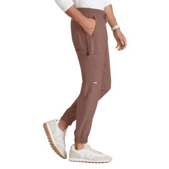 Brown jogger scrub pants with elastic waistband, cargo pockets, and elastic cuffs, shown with white sneakers.