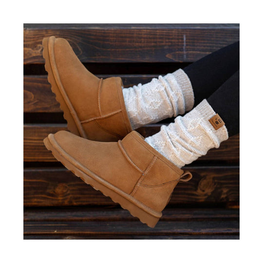 Tan suede ankle boots with fleece lining and cream socks on a wooden bench