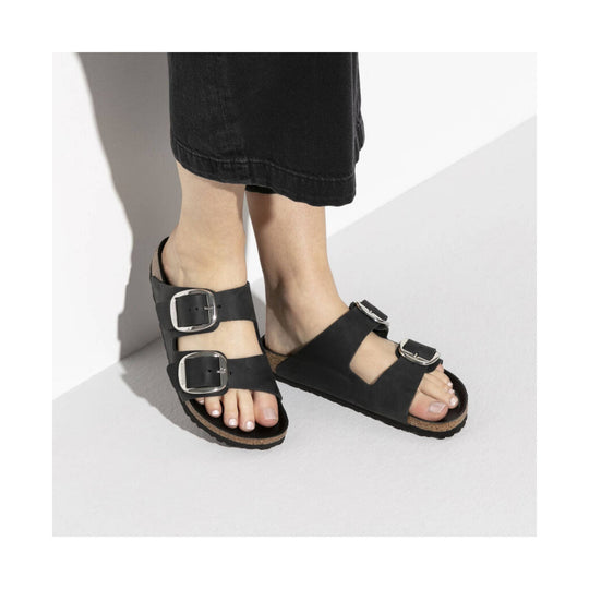 Black double-strap slide sandals with oversized silver buckles and cork footbeds