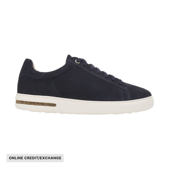 Dark low-top suede sneaker with white sole and cork stripe, shown in side view, with "ONLINE CREDIT/EXCHANGE" text.