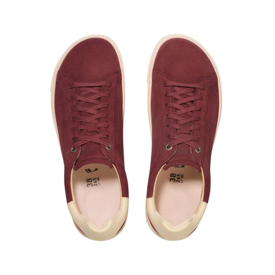 Pair of burgundy suede low-top sneakers with cream soles and laces, viewed from above