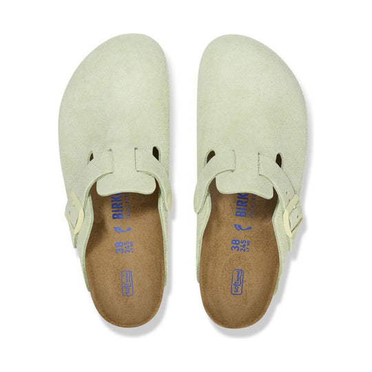 Pair of faded lime suede clogs with open backs, side buckles, and tan cork footbeds