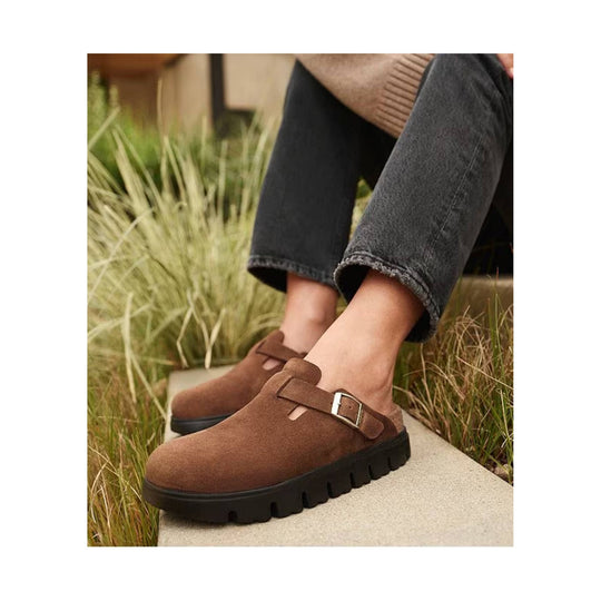 Brown suede clog-style mules with a buckle strap and thick black lug soles