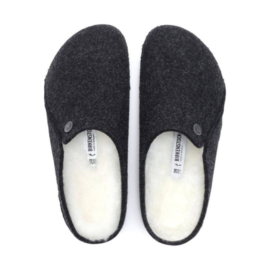 Pair of black felt slip-on clogs with white shearling lining, shown from above.