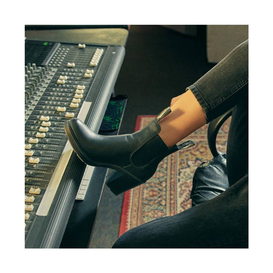 Person wearing black shoes sitting in front of a mixing console
