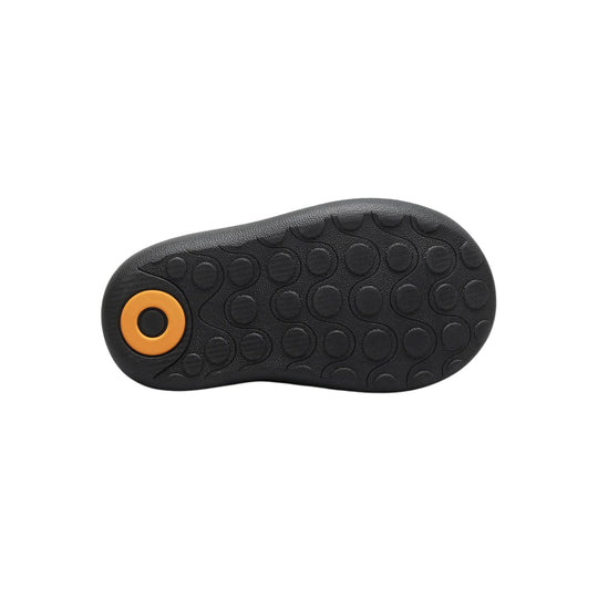 Black boot sole with textured tread and an orange circular accent