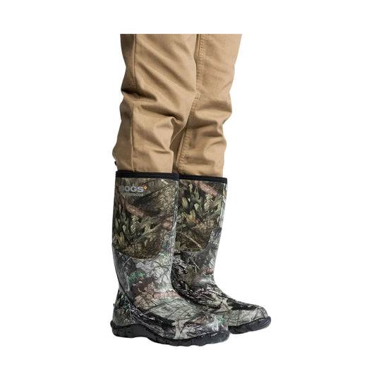 Camouflage rubber boots worn with beige pants on a white background