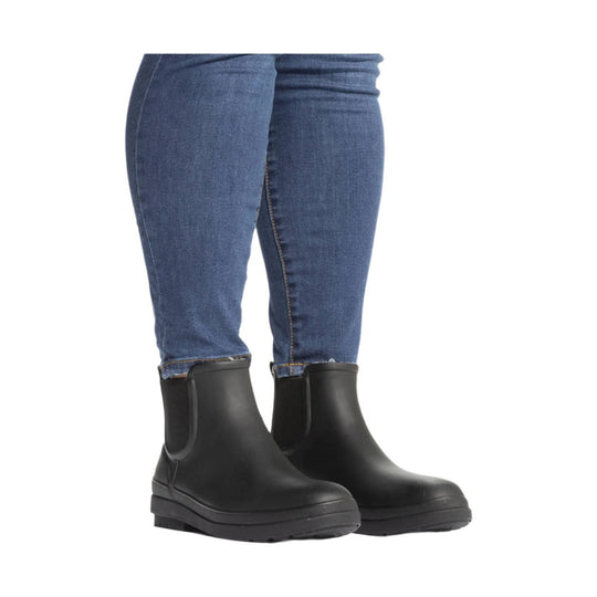 Black Chelsea-style rain boots with thick lug soles, shown on lower legs wearing blue jeans