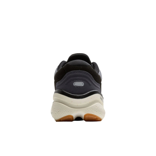 Rear view of a black, gray, and cream running shoe with a cushioned sole and gum outsole