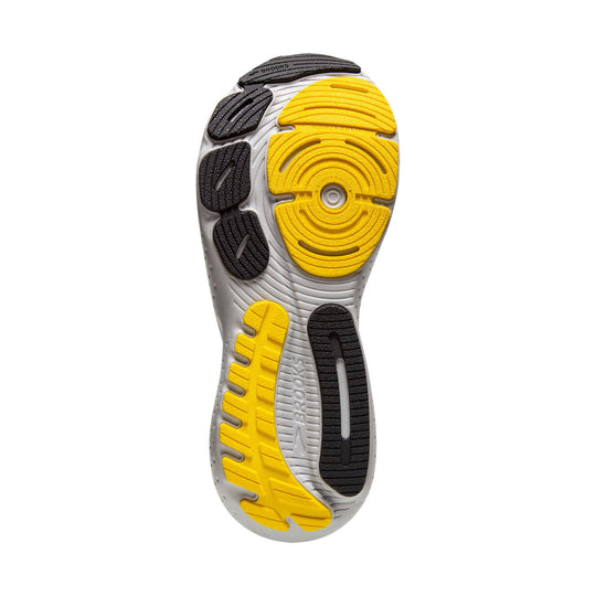 Running shoe outsole with yellow and black rubber tread on a gray sole