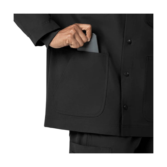 Black scrub coat with large front patch pockets and snap closure, shown with a hand reaching into the chest pocket