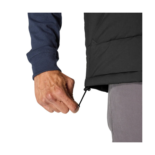 Close-up of a black insulated vest hem with drawcord adjustment beside a person’s hand and sleeve