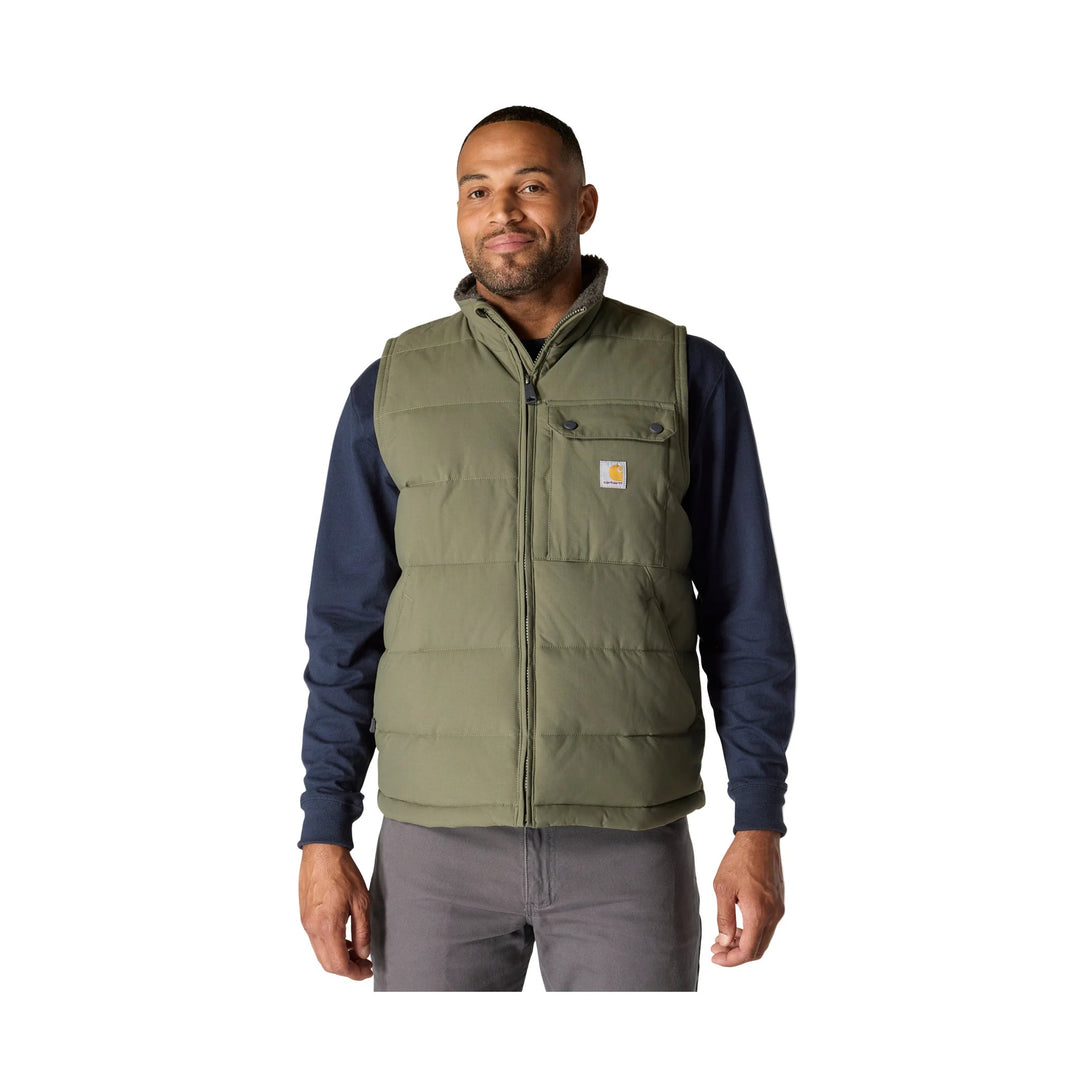 Olive insulated zip-front vest worn over a navy long-sleeve shirt