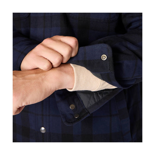 Navy plaid flannel shirt cuff with snap button, showing a cream cuffed sleeve underneath