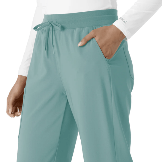 Teal scrub pants with elastic waistband, drawstring, and side pockets, shown on a model