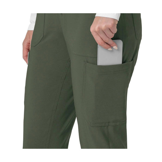 Olive scrub pants with cargo pockets, one holding a phone
