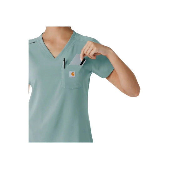 Light blue V-neck scrub top with chest pocket and pen slot, shown with a hand holding a card in the pocket